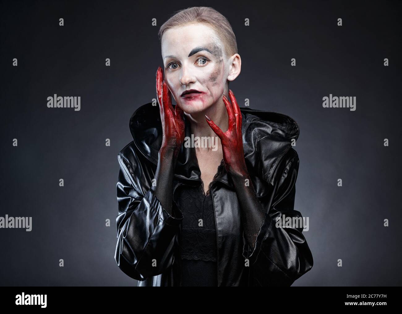 Photo d'une femme en imperméable noir aux mains rouges Banque D'Images