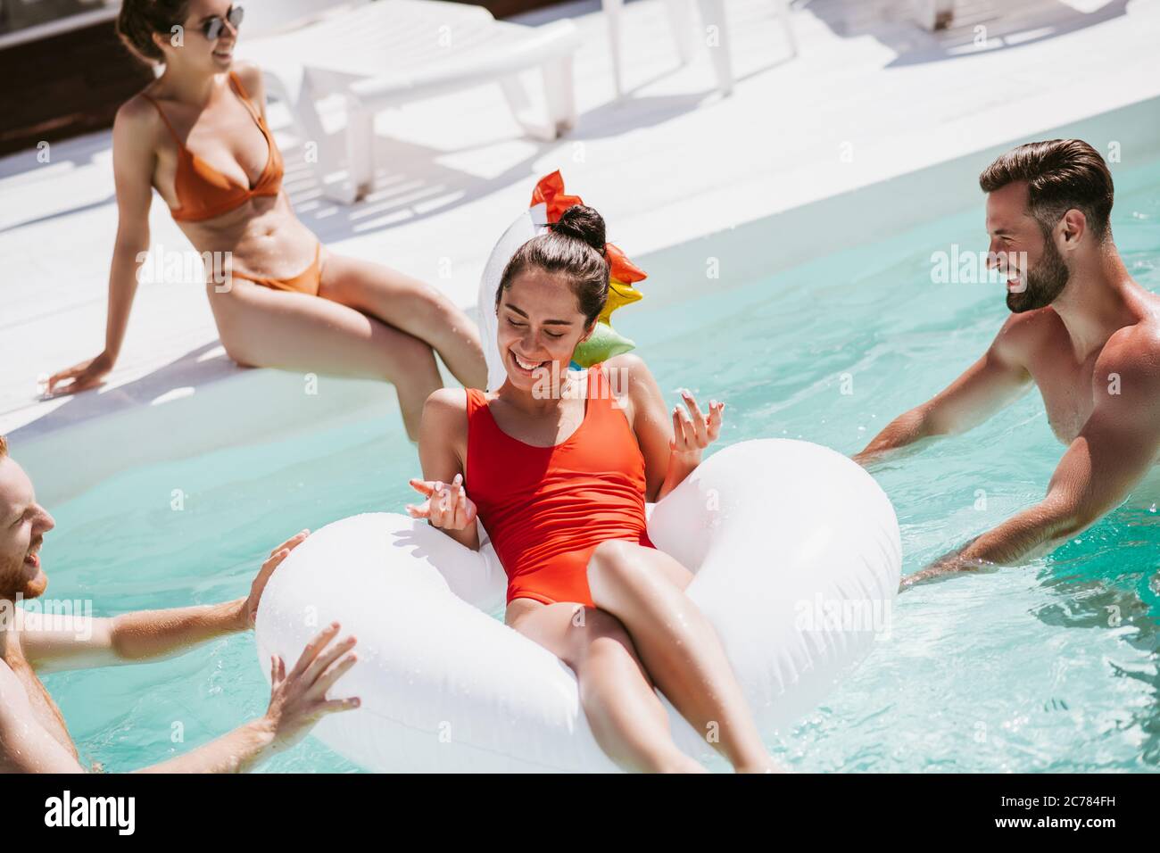 Belle femme aux cheveux sombres dans un maillot de bain rouge se friant sur un anneau de natation dans la piscine Banque D'Images