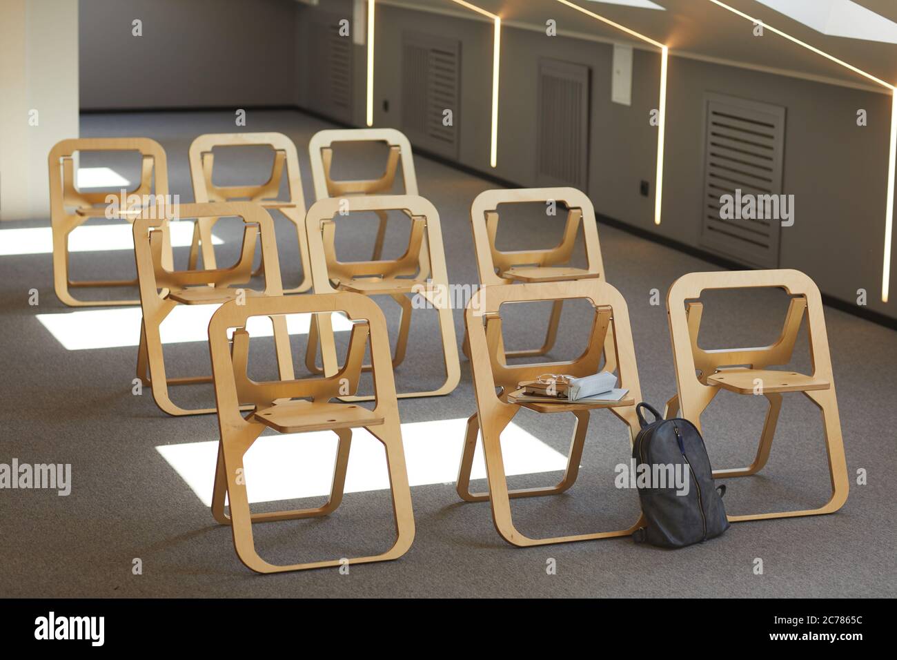Salle de conférence vide avec chaises pliantes modernes en bois dans les rangées et cartable près de l'un d'elle Banque D'Images