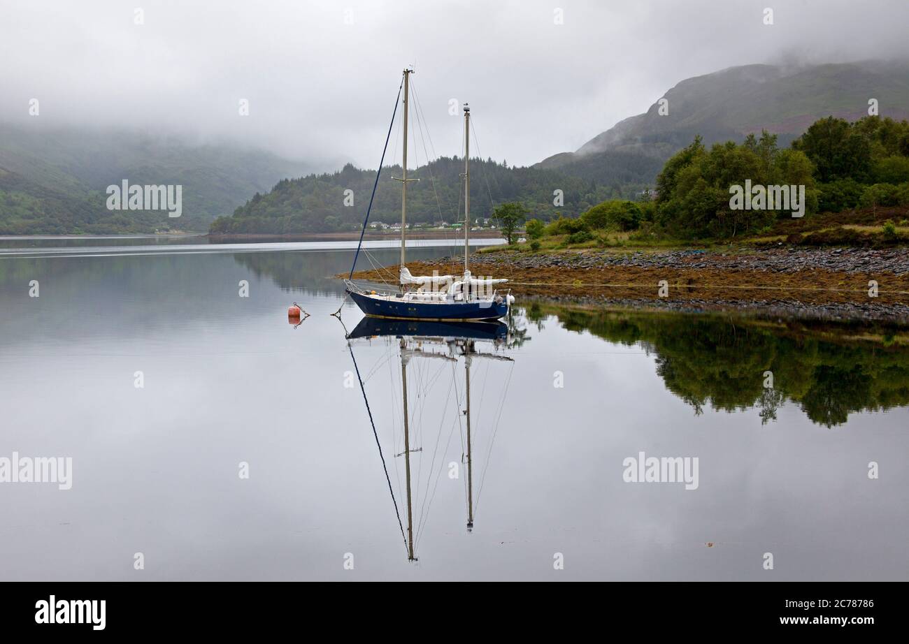 Ballachulish, Lochaber, Écosse, Royaume-Uni. 15 juillet 2020. Après une lourde pluie de nuit, le matin a commencé par la brume sur les collines et les montagnes en arrière-plan, avec peu ou pas de vent sur le Loch Leven permettant des réflexions presque parfaites de la petite embarcation et des conditions parfaites pour le milieu. La pluie s'est mise en place peu après pour accueillir les visiteurs qui s'aventuraient dans la région, car les grands hôtels sont autorisés à ouvrir, ainsi que les pubs et les bars pouvant servir les clients à l'intérieur. Banque D'Images