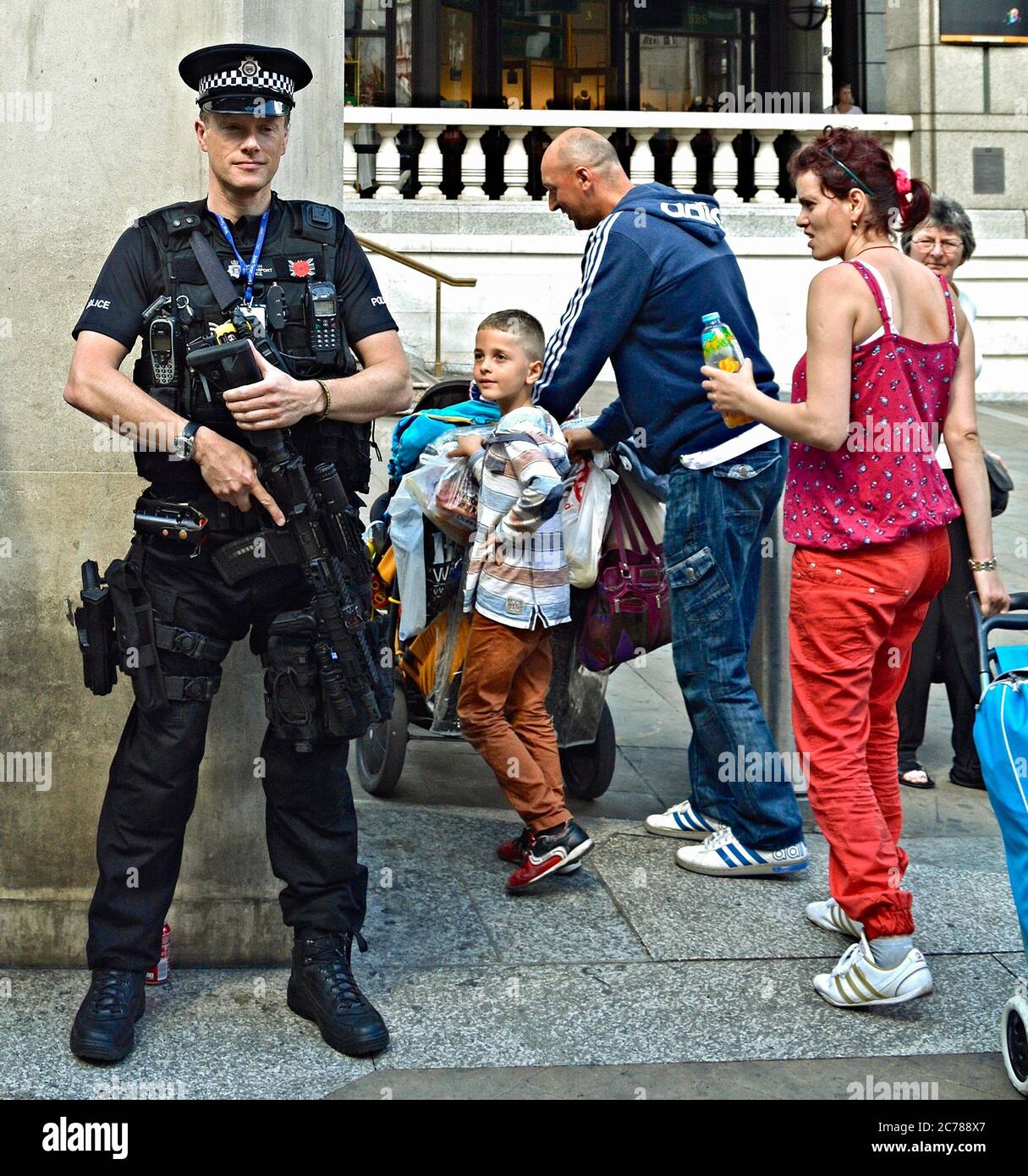 Un jeune garçon admirant un policier armé anti-terroriste qui se tient debout devant la gare de Liverpool Street à Londres, en Angleterre, au Royaume-Uni Banque D'Images