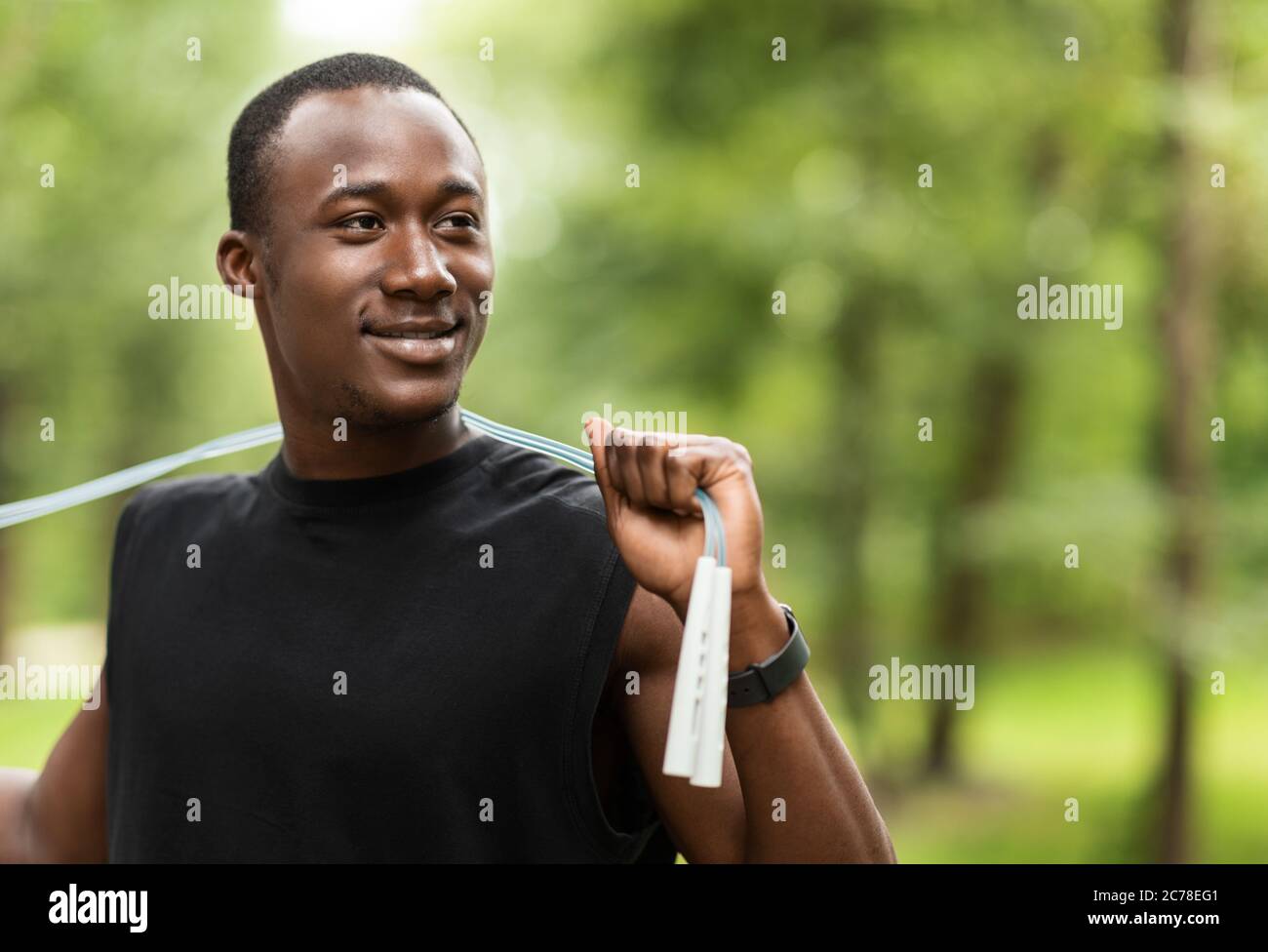 Homme sportif souriant avec entraînement de corde de saut au parc Banque D'Images