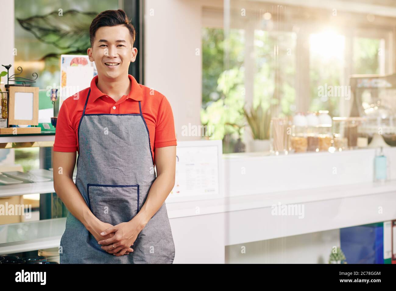 Portrait du jeune propriétaire vietnamien souriant du café debout au comptoir Banque D'Images