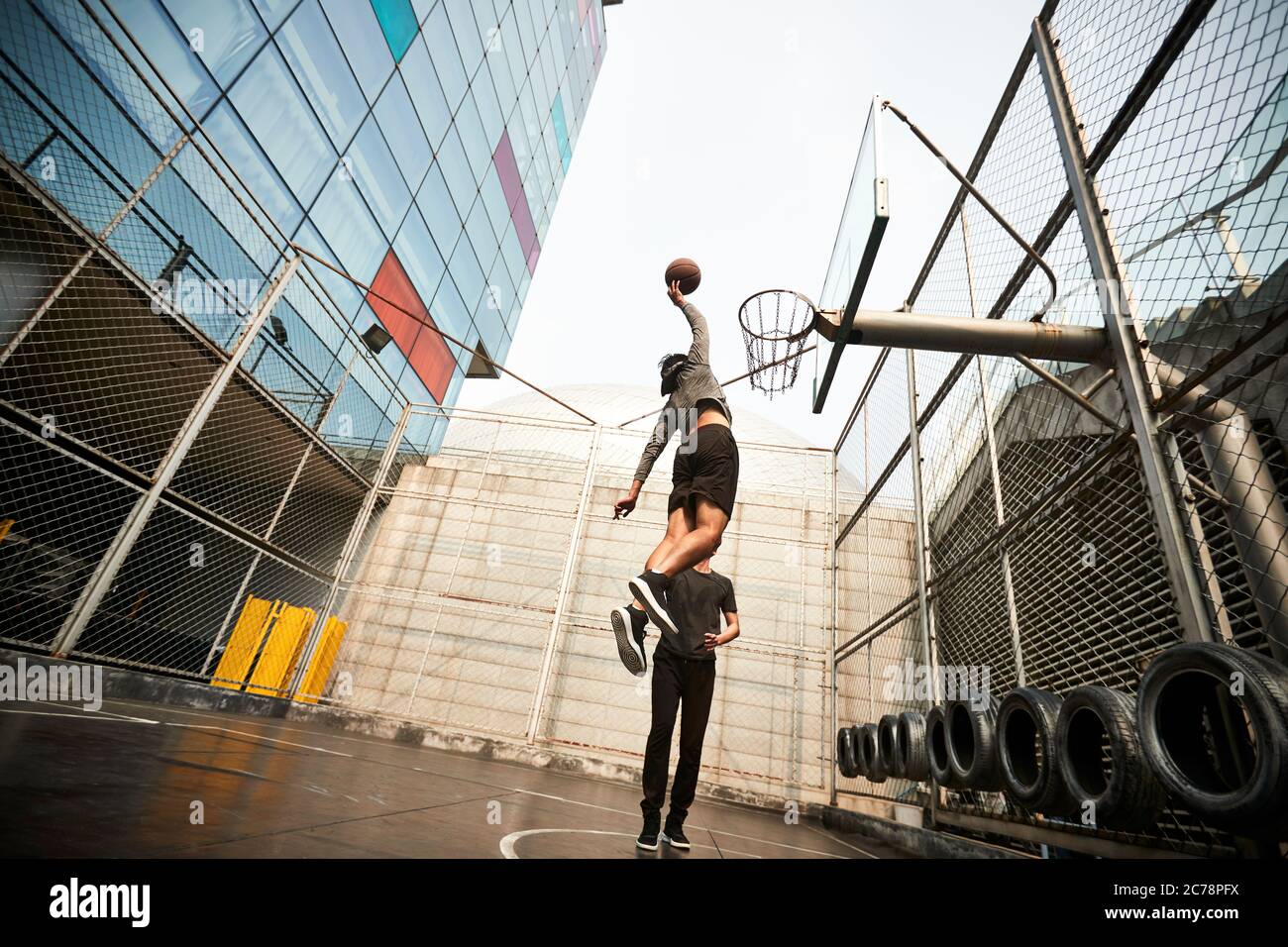 un jeune joueur asiatique de basket-ball dunking le ballon sur un terrain extérieur Banque D'Images