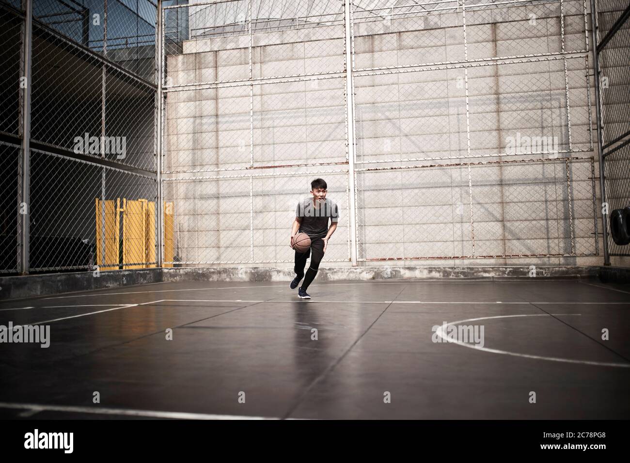 un jeune homme asiatique essaie de jouer un dunk sur un terrain extérieur Banque D'Images