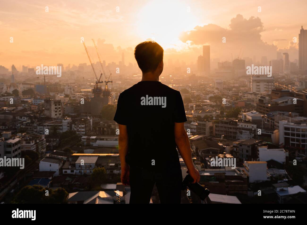 Jeune homme asiatique avec caméra au sommet du bâtiment et vue sur le lever du soleil sur la ville de Bangkok en Thaïlande Banque D'Images