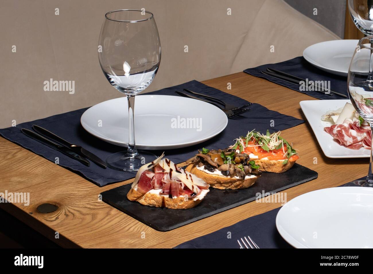 Trois bruschettas de pain tranché, champignons, saumon et viande sur une table en bois au restaurant. Collations et sandwichs Banque D'Images
