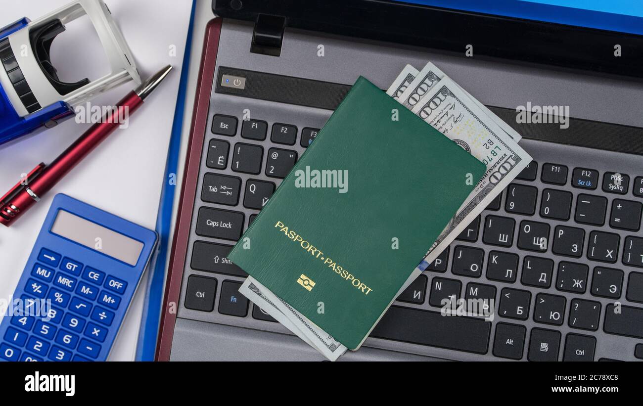Passeport vert avec dollars américains sur le clavier d'ordinateur portable. Inscription en ligne. Concept - corruption et briber. Vue de dessus Banque D'Images