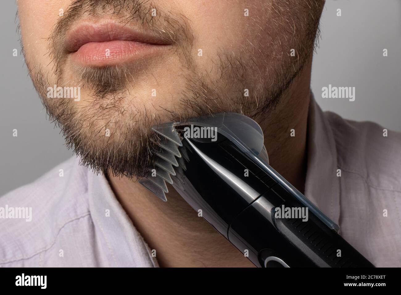 Un homme rasages sa barbe avec un rasoir de tondeuse. La barbe à modeler,  le style masculin, les soins des cheveux du visage, les routines matinales dans  la salle de bains Photo