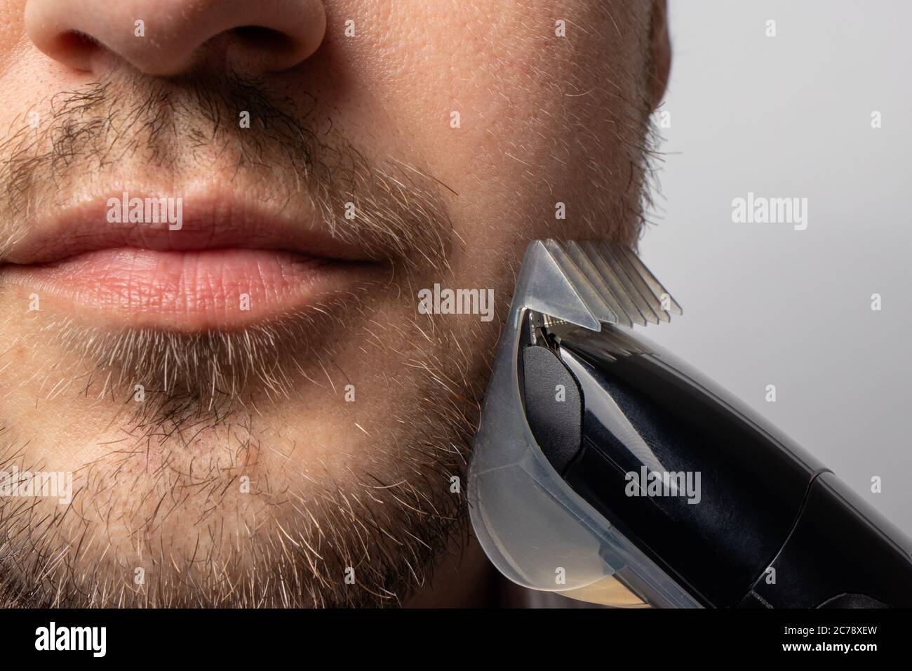 Un homme rasages sa barbe avec un rasoir de tondeuse. La barbe à modeler,  le style masculin, les soins des cheveux du visage, les routines matinales dans  la salle de bains Photo