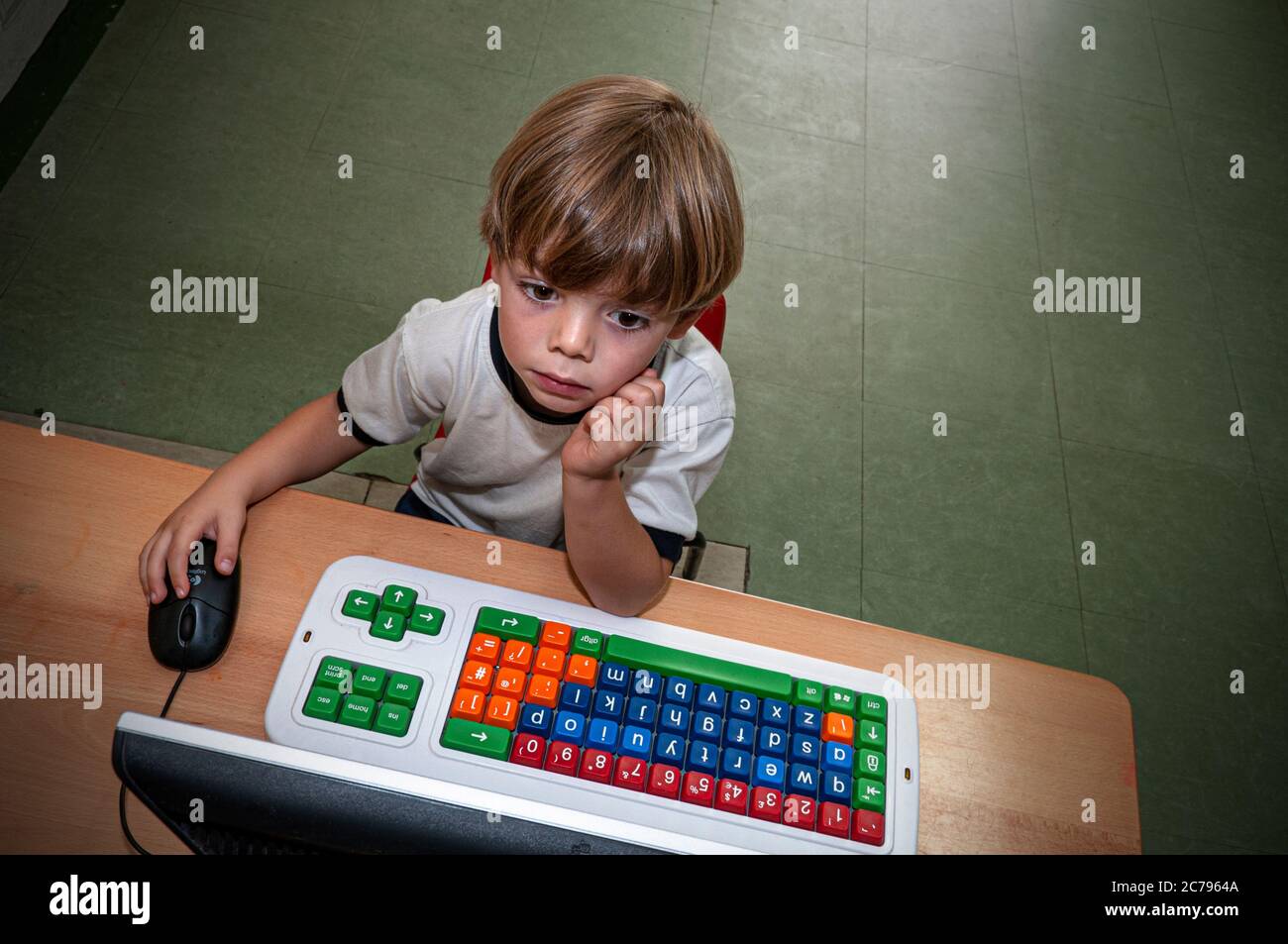 Petit garçon ordinateur Internet maternelle en ligne enfant 4-6 ans études pensives à l'école maternelle ordinateur avec souris dans la salle de classe de réception Banque D'Images