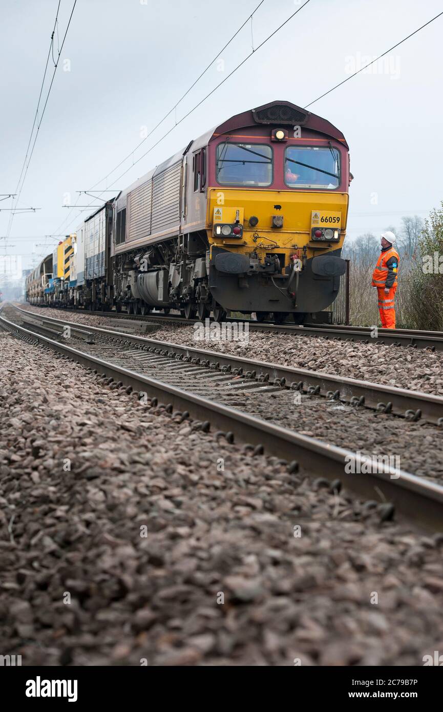 Locomotive diesel de classe 66 dans la livrée EWS transportant des wagons de ballast de réseau ferroviaire sur une partie de chemin de fer au Royaume-Uni. Banque D'Images