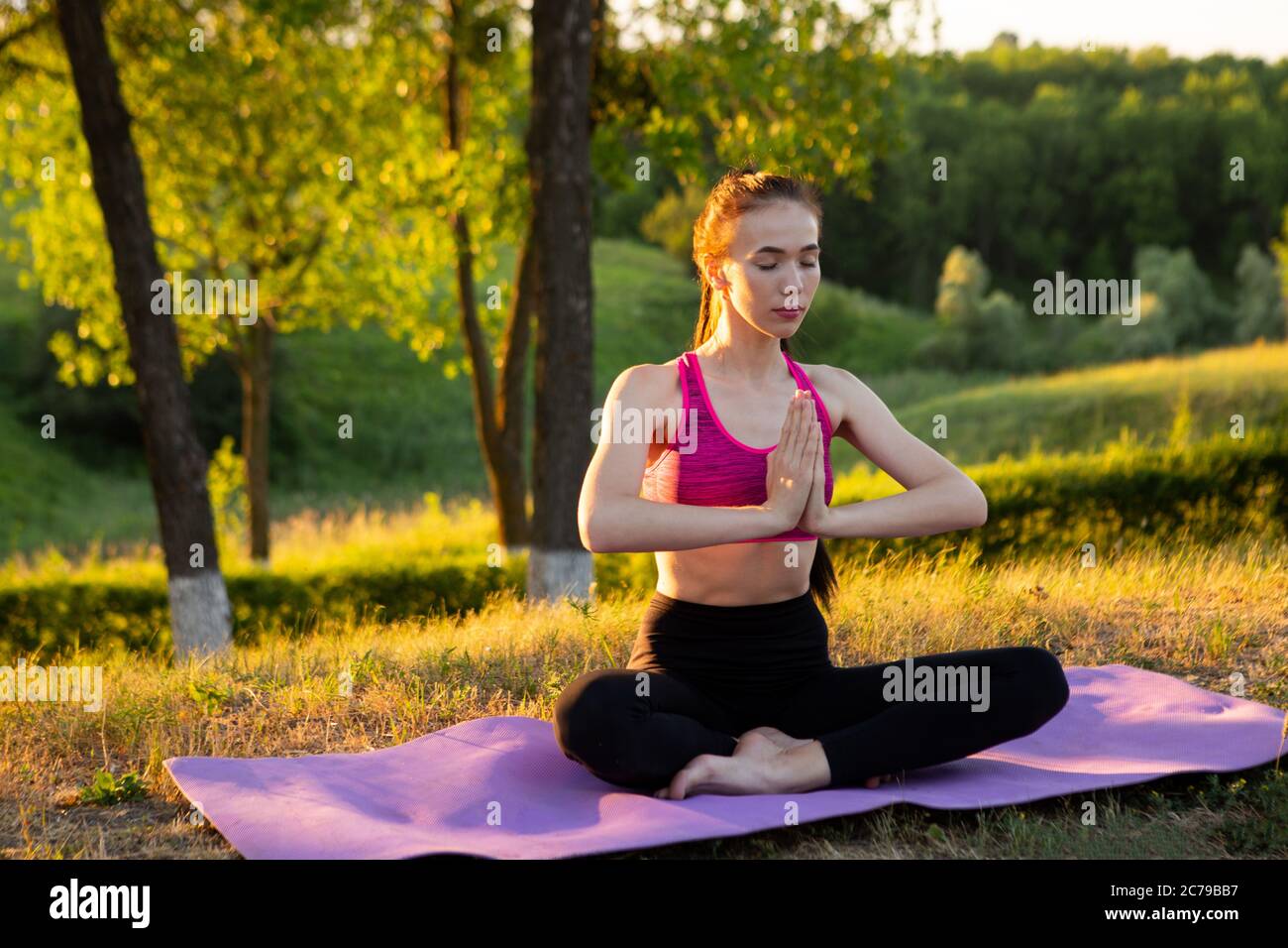 Une femme sans chaussures est assise sur un tapis et pratique le yoga. Banque D'Images