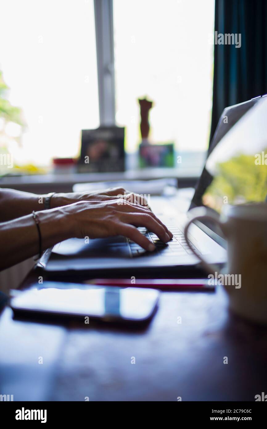 Mains d'une femme qui tape sur un ordinateur portable travaillant à domicile Banque D'Images
