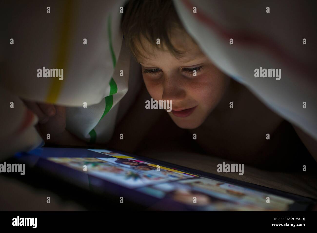 Gros plan sur un garçon en utilisant une tablette numérique sous une couverture Banque D'Images