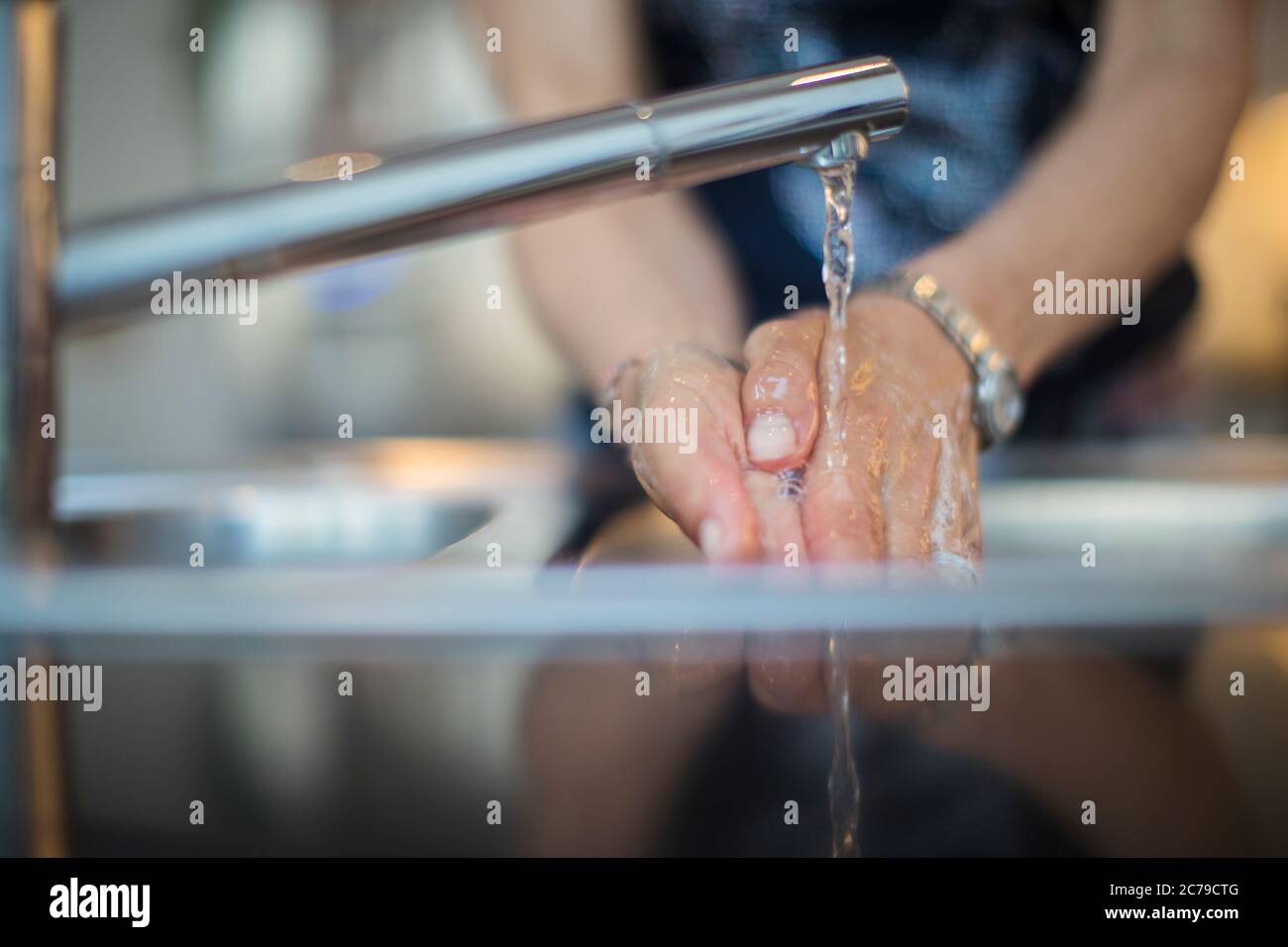 Une femme se lave les mains près de l'évier de cuisine Banque D'Images