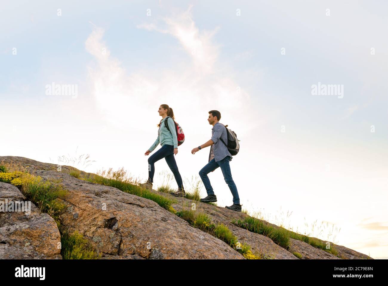 Couple de jeunes voyageurs heureux randonnée avec des sacs à dos sur le sentier Rocky Trail en soirée. Voyage en famille et aventure Banque D'Images