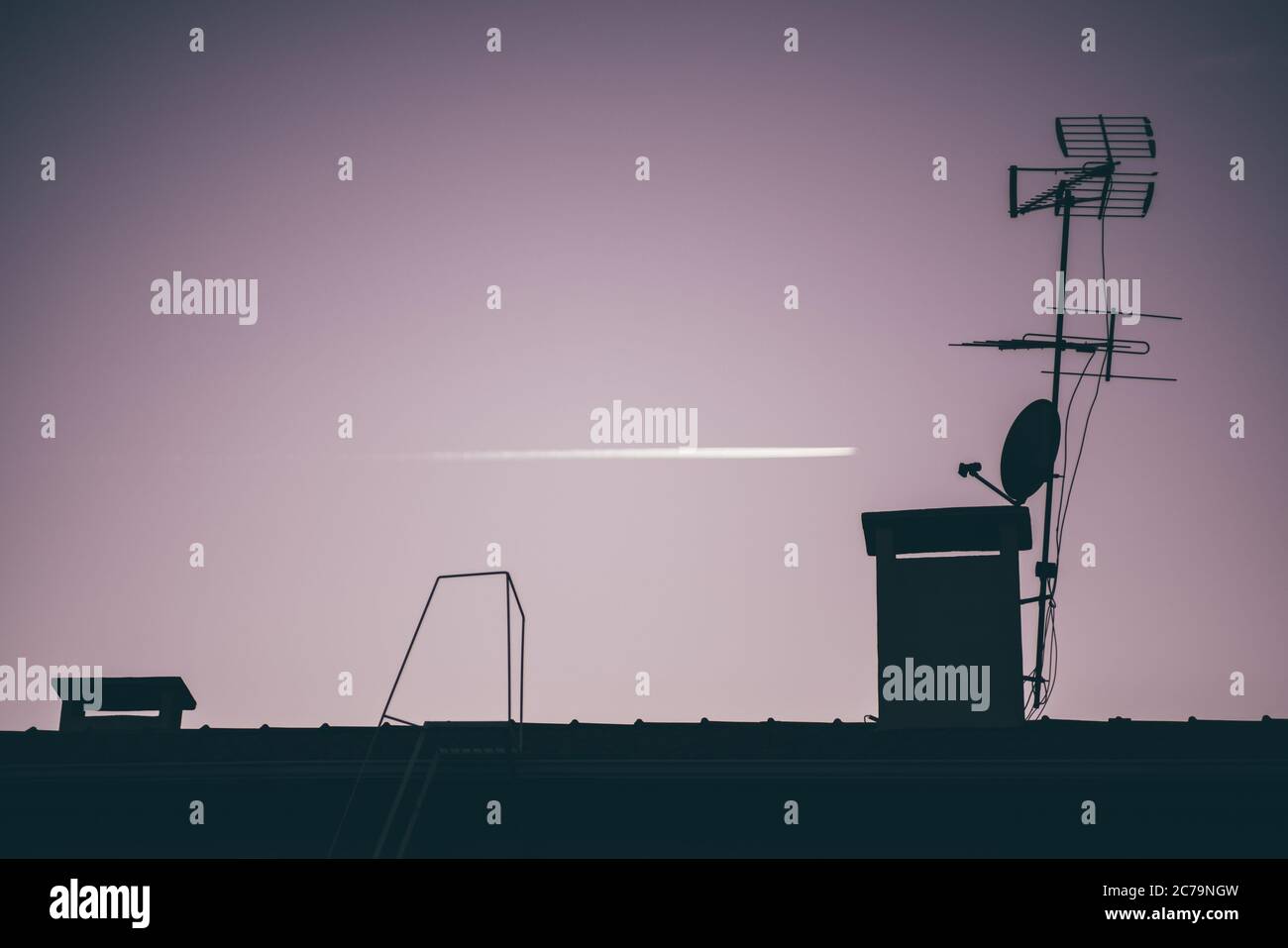 Photo nocturne sombre avec mise au point sélective sur une silhouette du toit avec antennes et tuyaux de ventilation au-dessus au premier plan et tracé Banque D'Images