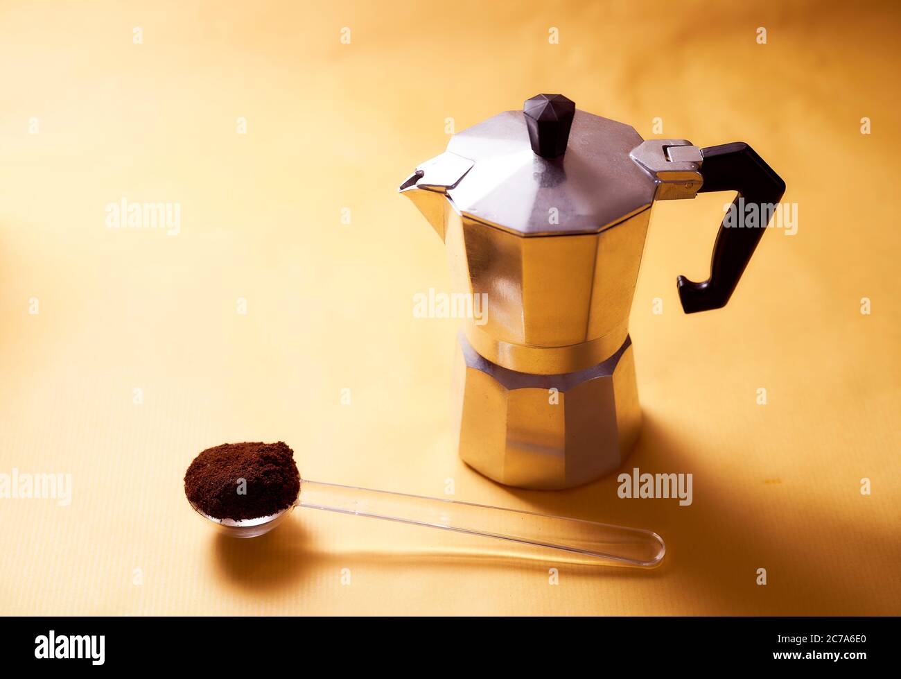 cafetière geyser avec café frais et cuillère sur fond jaune Banque D'Images