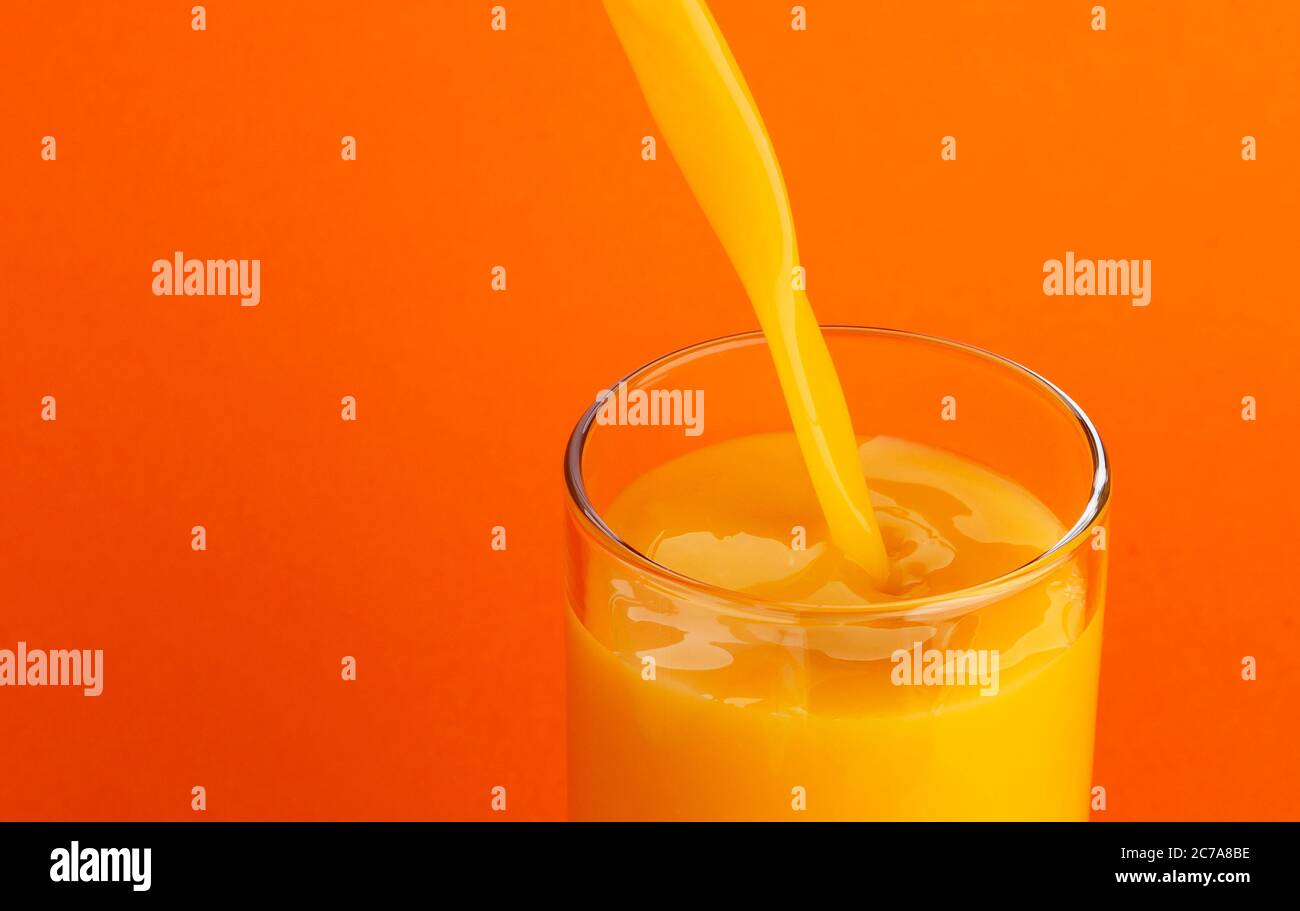 Jus d'orange versé dans le verre, isolé sur fond de couleur, avec espace de copie Banque D'Images