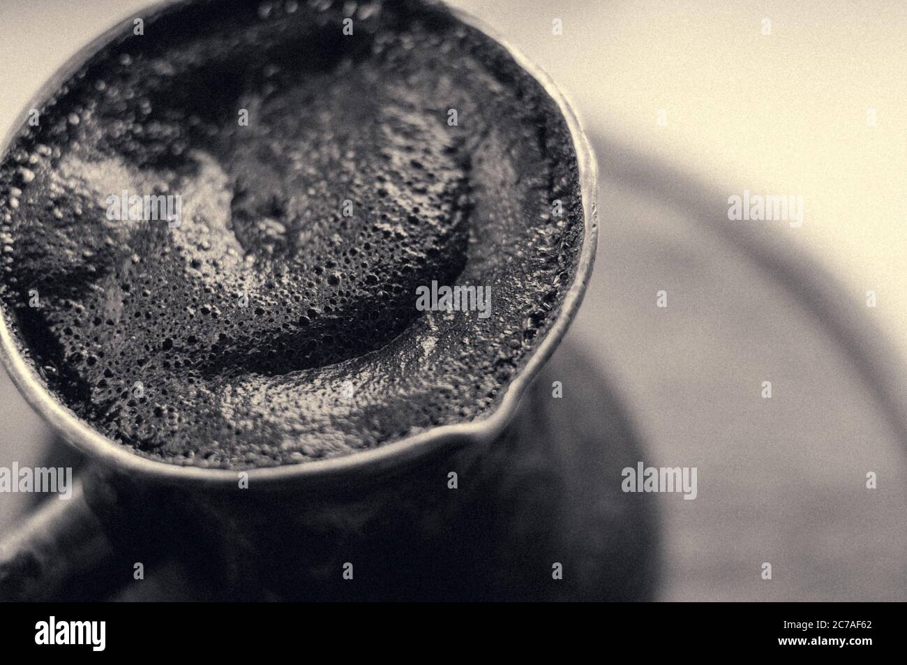 Café naturel avec mousse épaisse, brassé dans une cève de cuivre de la manière classique, sur un fond de bois, photo macro. Banque D'Images