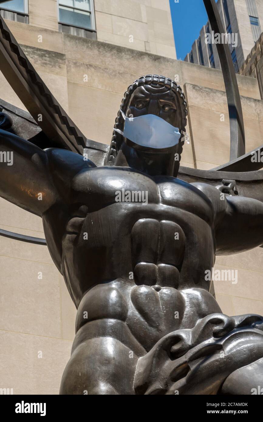L'ancien Titan grec Atlas tenant les cieux Bronze Armillary sphère Sculpture au Rockefeller Center portant un masque de visage dû à COVID-19, NYC, USA Banque D'Images