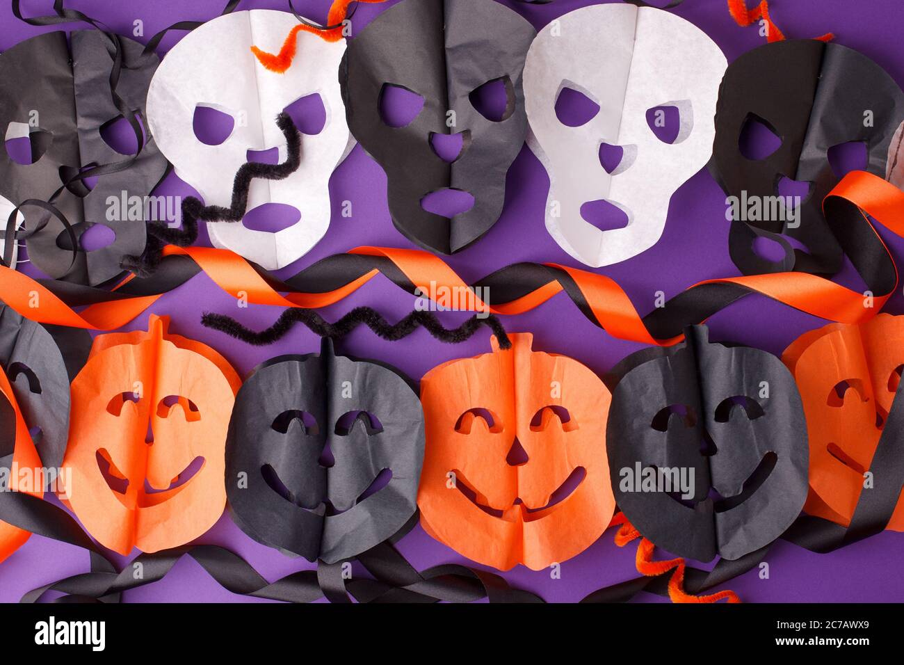 Halloween, vacances et décoration concept - citrouilles et guirlande de têtes de mort Jack-o-lanternes sur fond violet, traditionnel automne octobre fête décor, s Banque D'Images