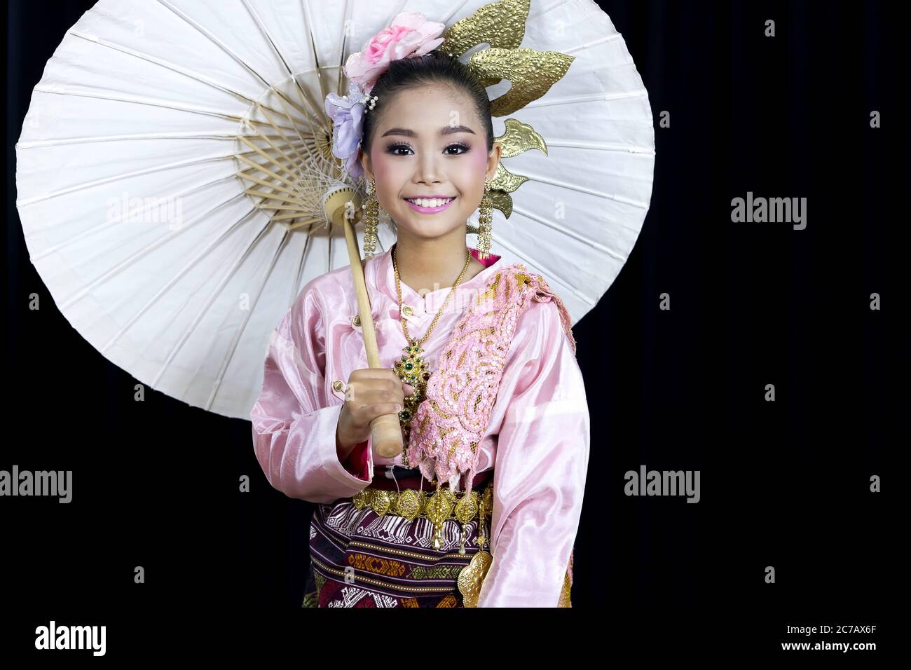 Une image isolée avec fond noir d'une fille asiatique vêtue de costumes traditionnels et tenant un parapluie en papier, un célèbre artisanat dans le nord Banque D'Images