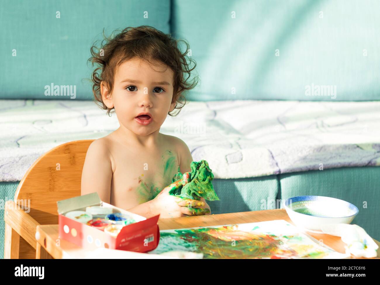 une jolie petite fille peint avec des peintures pour les doigts dans sa chambre. Banque D'Images