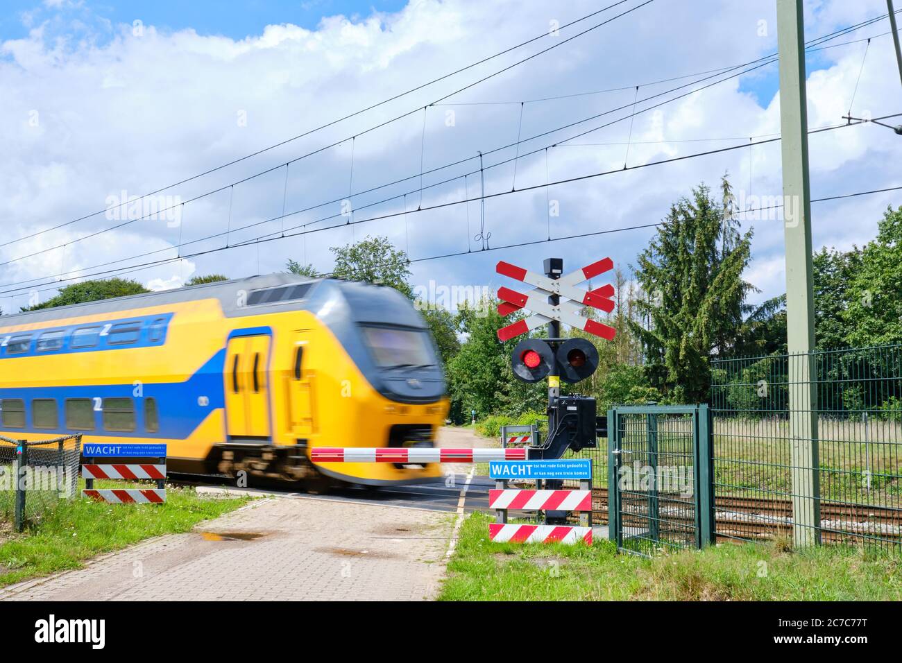 Passage de chemin de fer avec barrières et feux rouges clignotants et train à grande vitesse peu tranchant. Texte hollandais, attendre jusqu'à ce que la lumière rouge soit disparu, possibilité d'autre train Banque D'Images