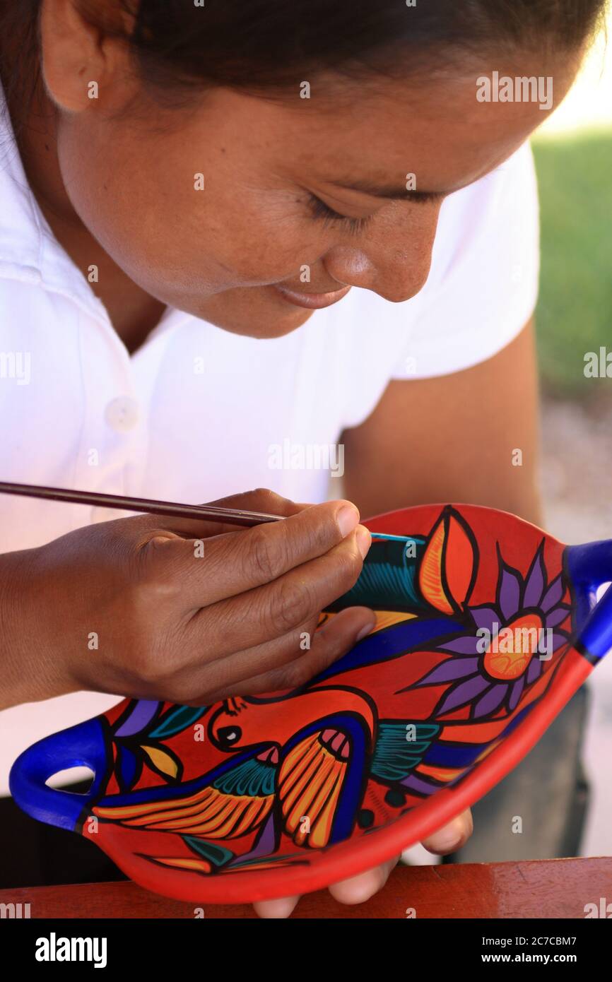 Akumal, Quintana Roo, Mexique - 26 novembre 2006 : jeune artiste maya peint une plaque en céramique traditionnelle colorée avec des motifs typiques mayas. Banque D'Images