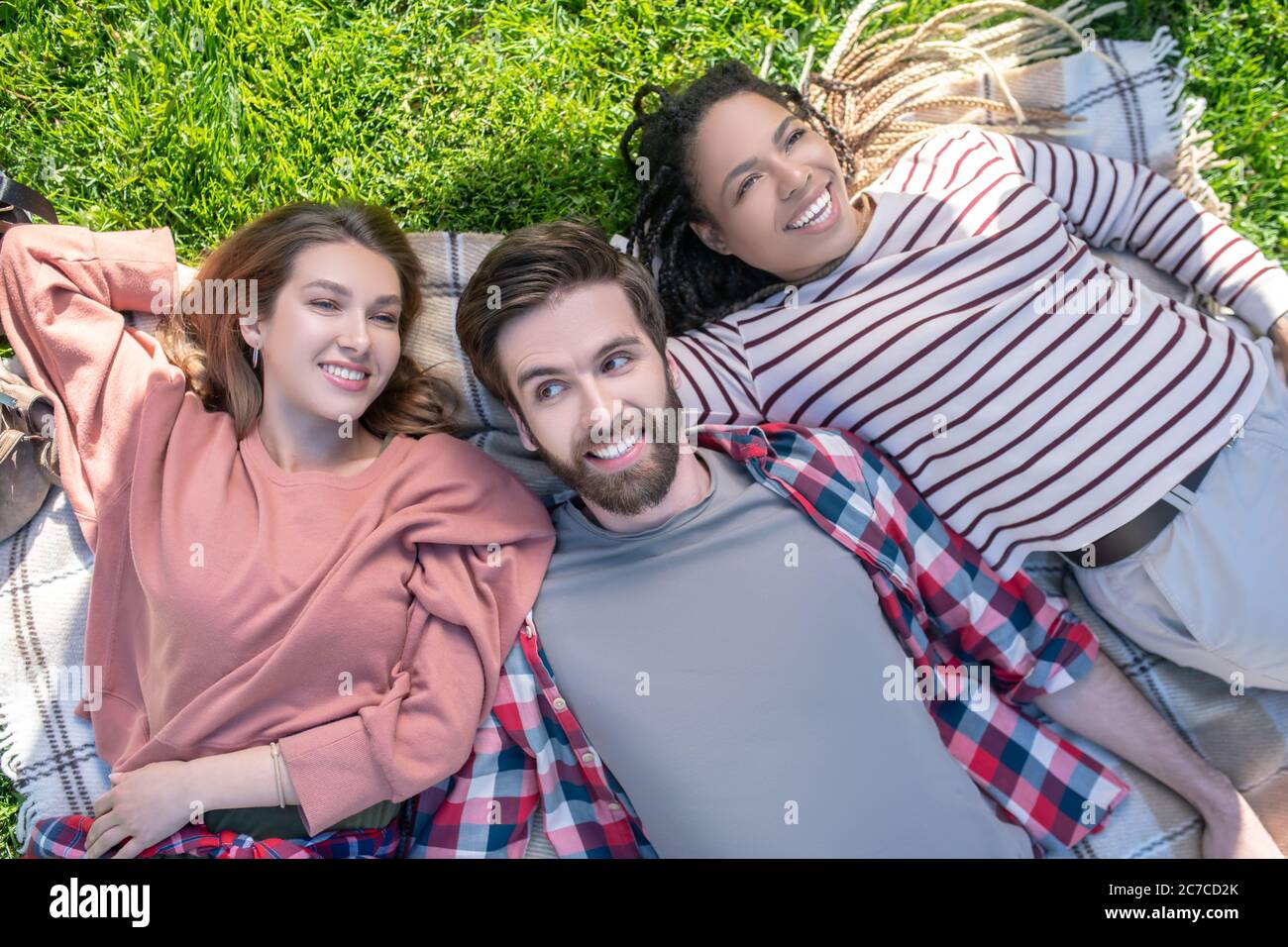 Guy et deux filles allongé sur un tissu écossais sur l'herbe Banque D'Images