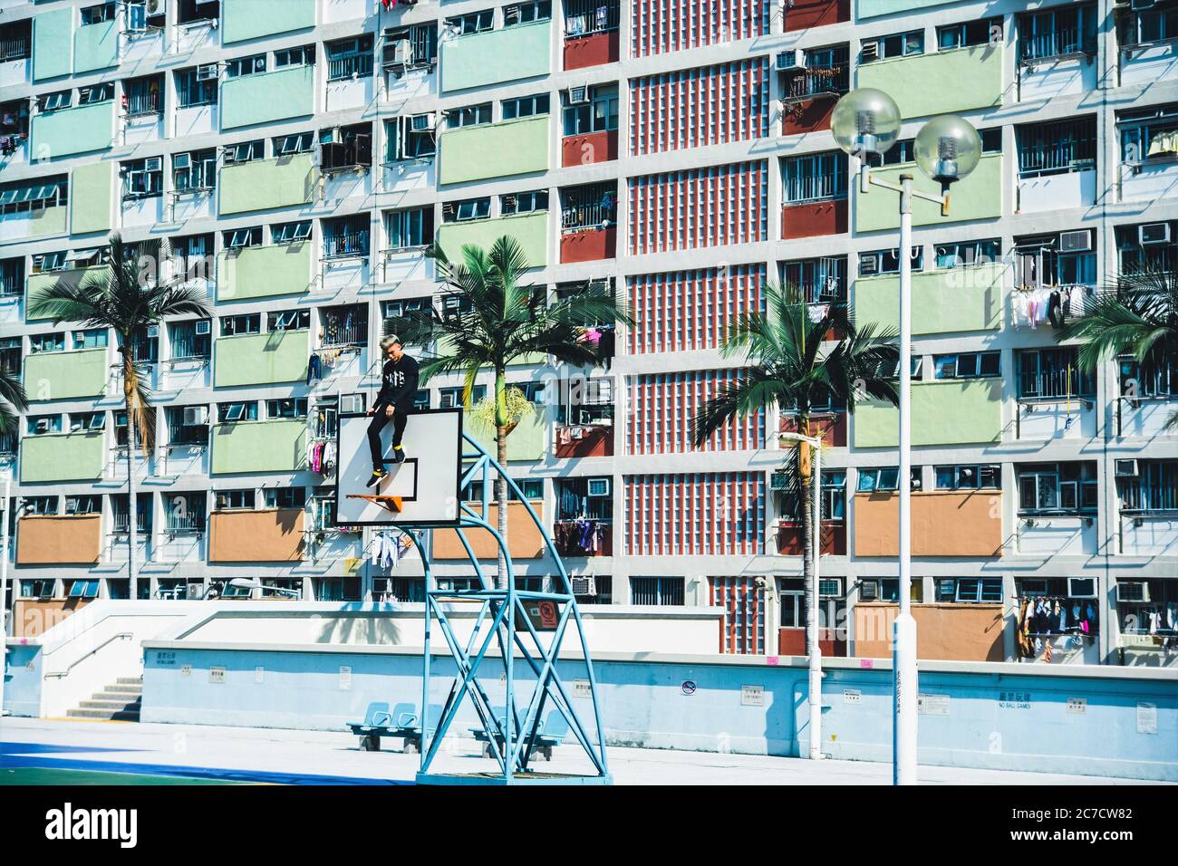 Gros plan d'un homme assis sur un panier de basket-ball près des bâtiments Banque D'Images