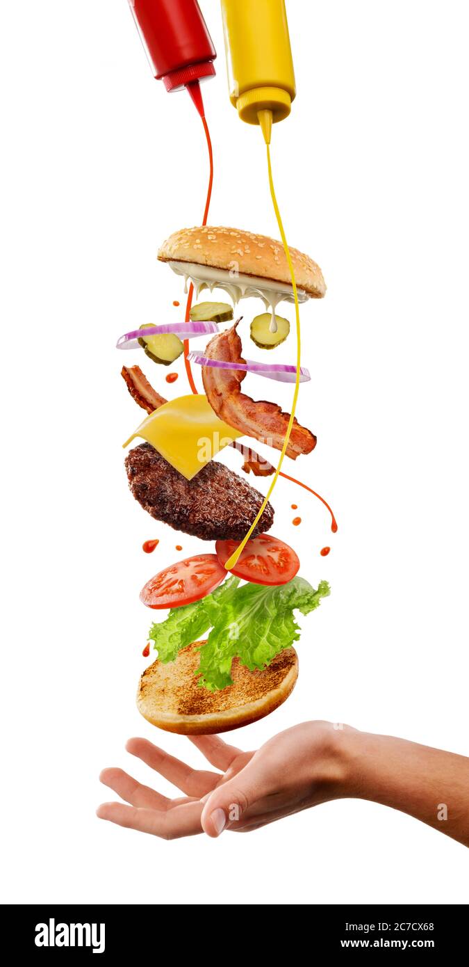 Cuisine créative du hamburger. Ingrédients volants, moutarde et ketchup Banque D'Images