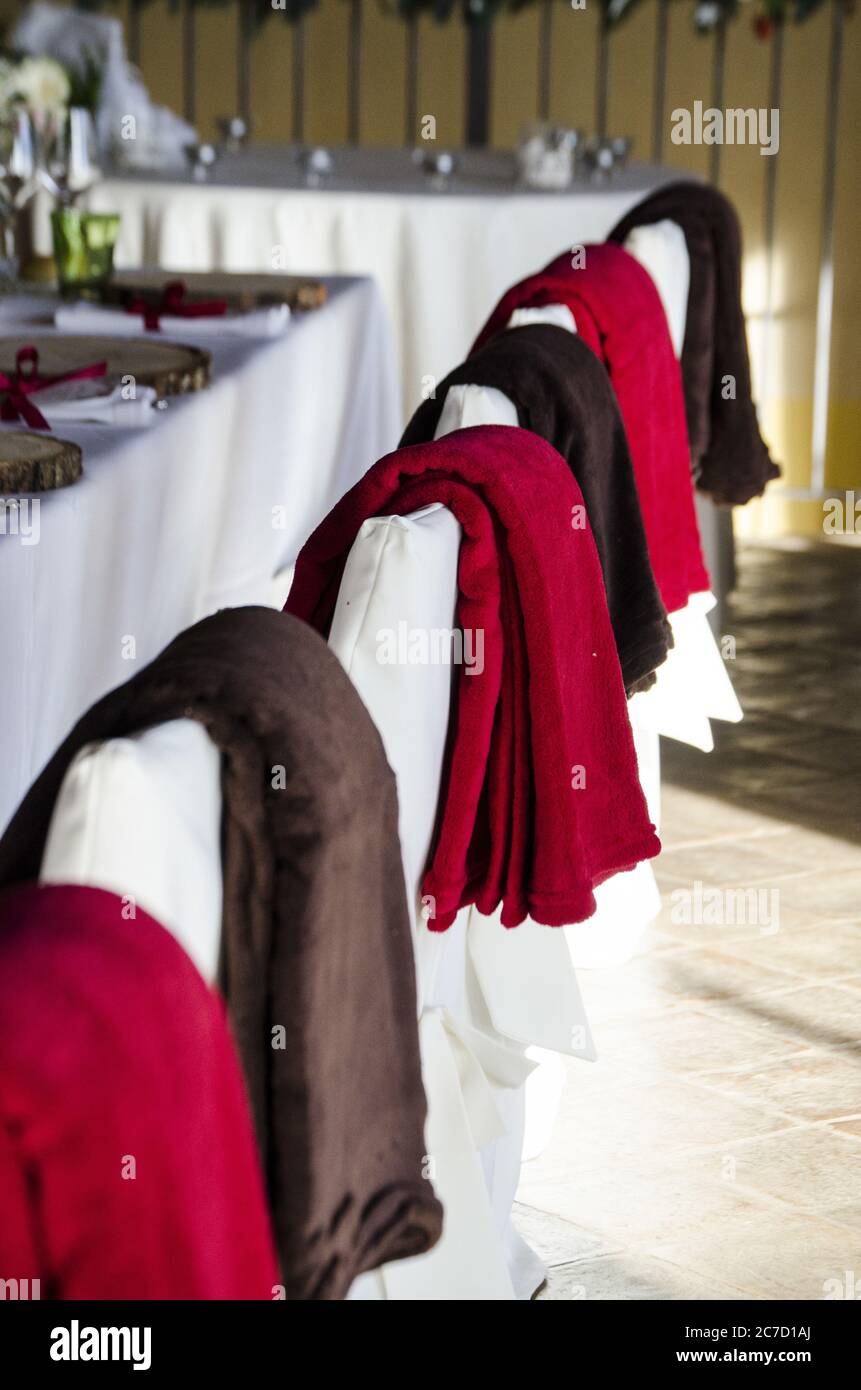 Gros plan sélectif vertical des couvertures marron et rouge chaises blanches près d'une table Banque D'Images