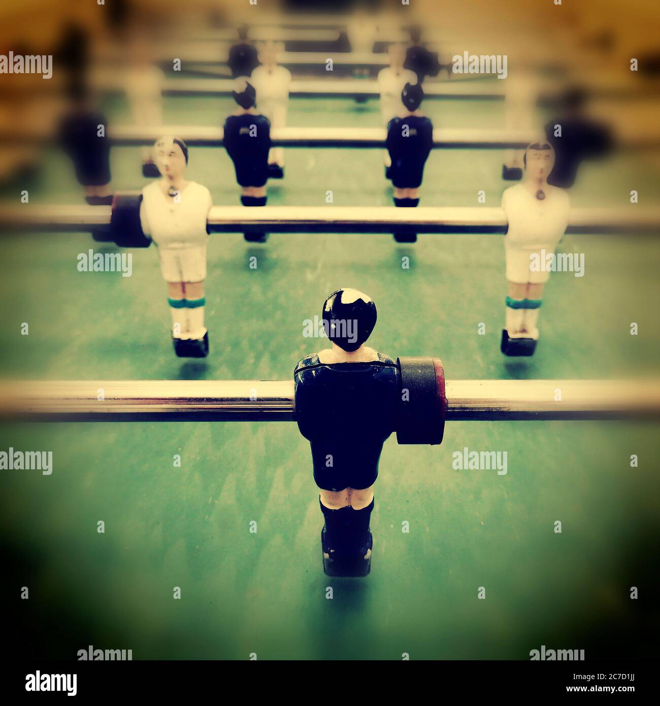 Joueurs de baby-foot prêts à l'action sur un terrain de jeu coloré lors d'un match amical dans un café animé Banque D'Images