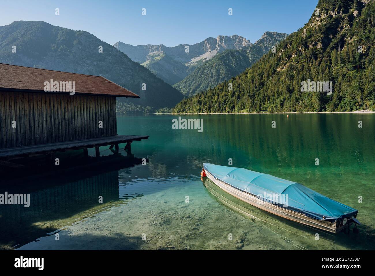 Petit bateau sur le lac Crystal Clear Plansee dans les Alpes européennes, en Autriche au lever du soleil tôt le matin Banque D'Images