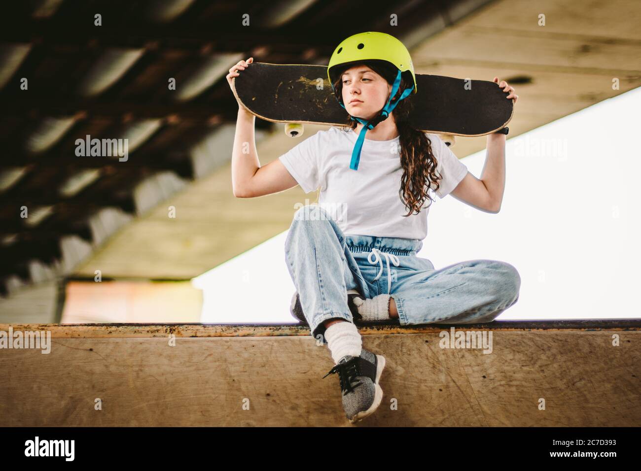 Une adolescente en casque et des vêtements élégants posant sur une rampe à  demi-pipe, un parc de skate extérieur. Magnifique skate modèle femme enfant  avec planche à roulettes Photo Stock - Alamy