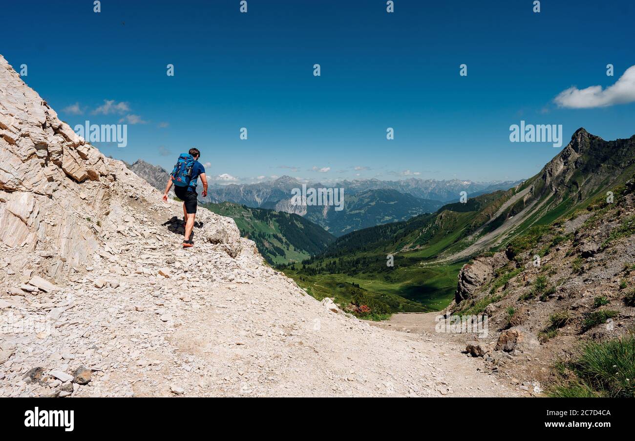 Grimpeur avec un sac à dos sur un jour ensoleillé, un homme s'est mis sur la montagne, les gens voyageant à travers la belle nature sauvage. Vacances en paysage Banque D'Images