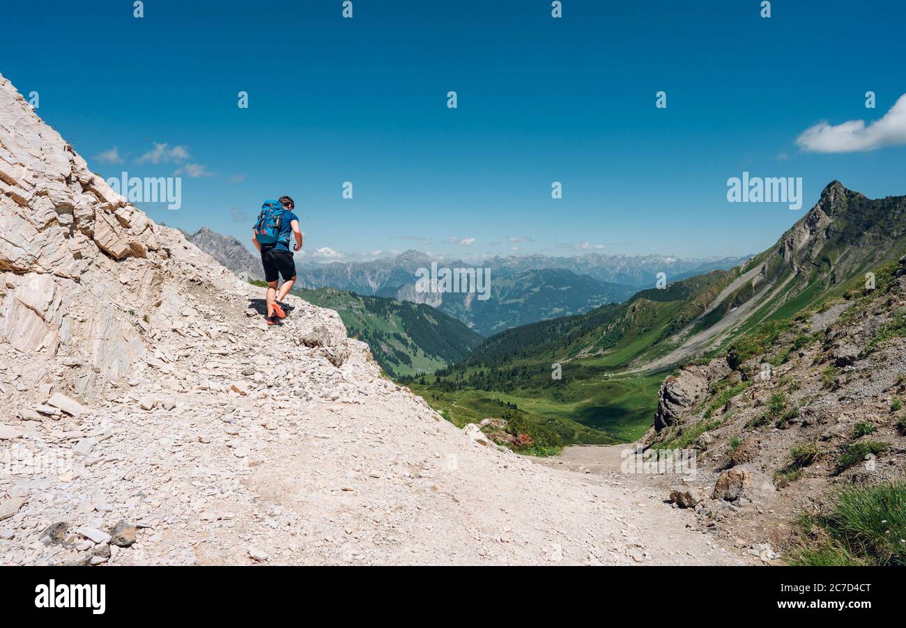 Grimpeur avec un sac à dos sur un jour ensoleillé, un homme s'est mis sur la montagne, les gens voyageant à travers la belle nature sauvage. Vacances en paysage Banque D'Images