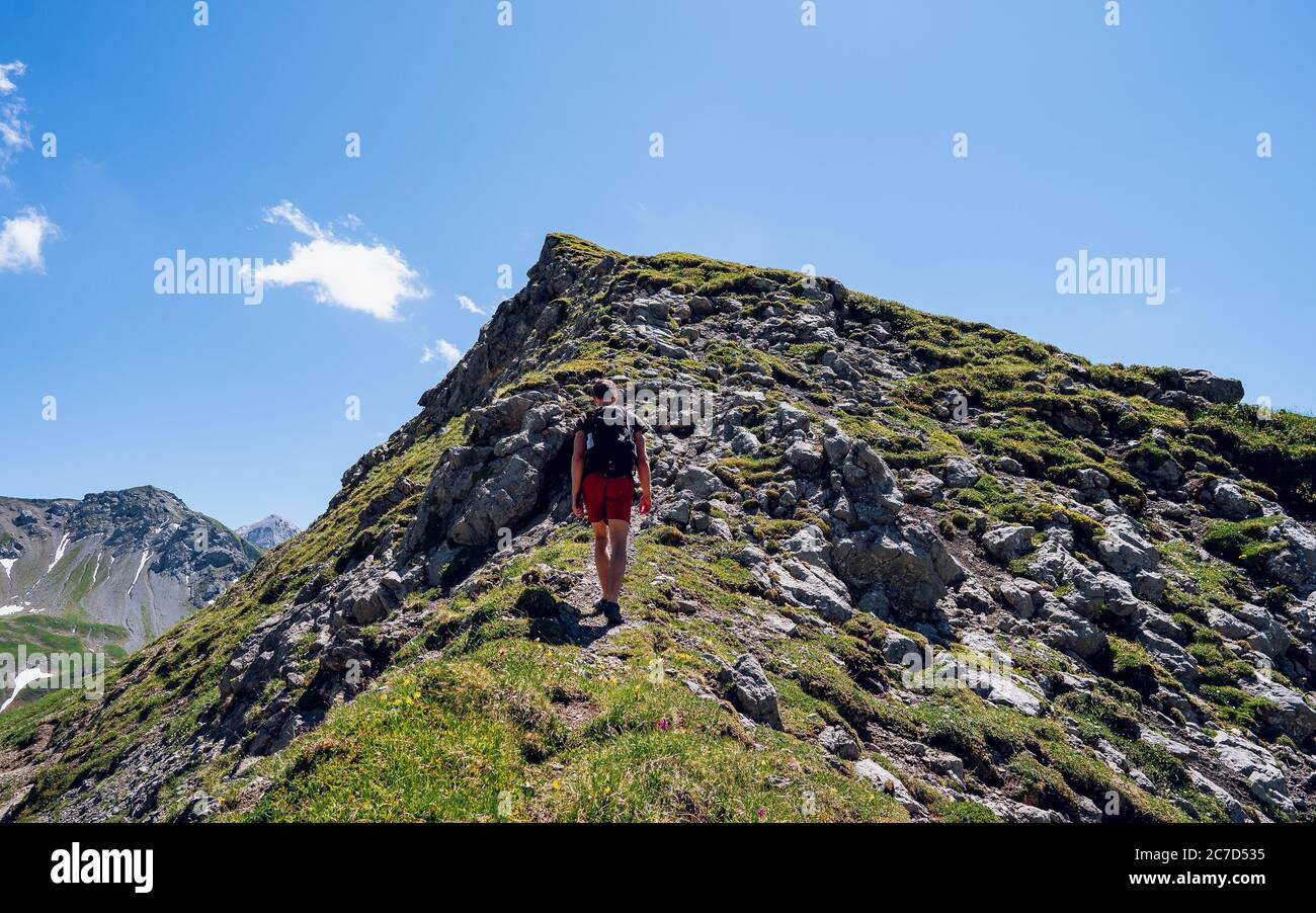 Grimpeur avec un sac à dos sur un jour ensoleillé, un homme s'est mis sur la montagne, les gens voyageant à travers la belle nature sauvage. Vacances en paysage Banque D'Images