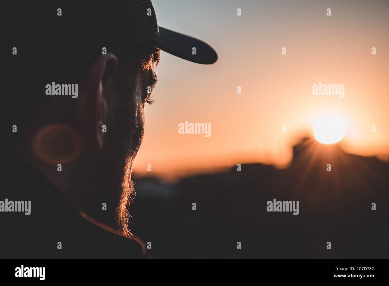 Photo peu profonde du profil d'un homme portant une casquette et regarder  le coucher de soleil flou Photo Stock - Alamy