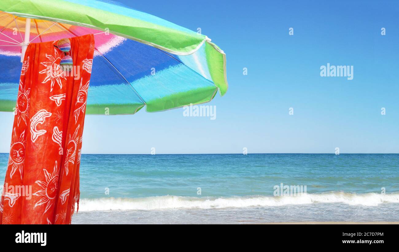 parasol, paréo et lunettes de soleil contre l'horizon marin et ciel clair, espace de copie Banque D'Images