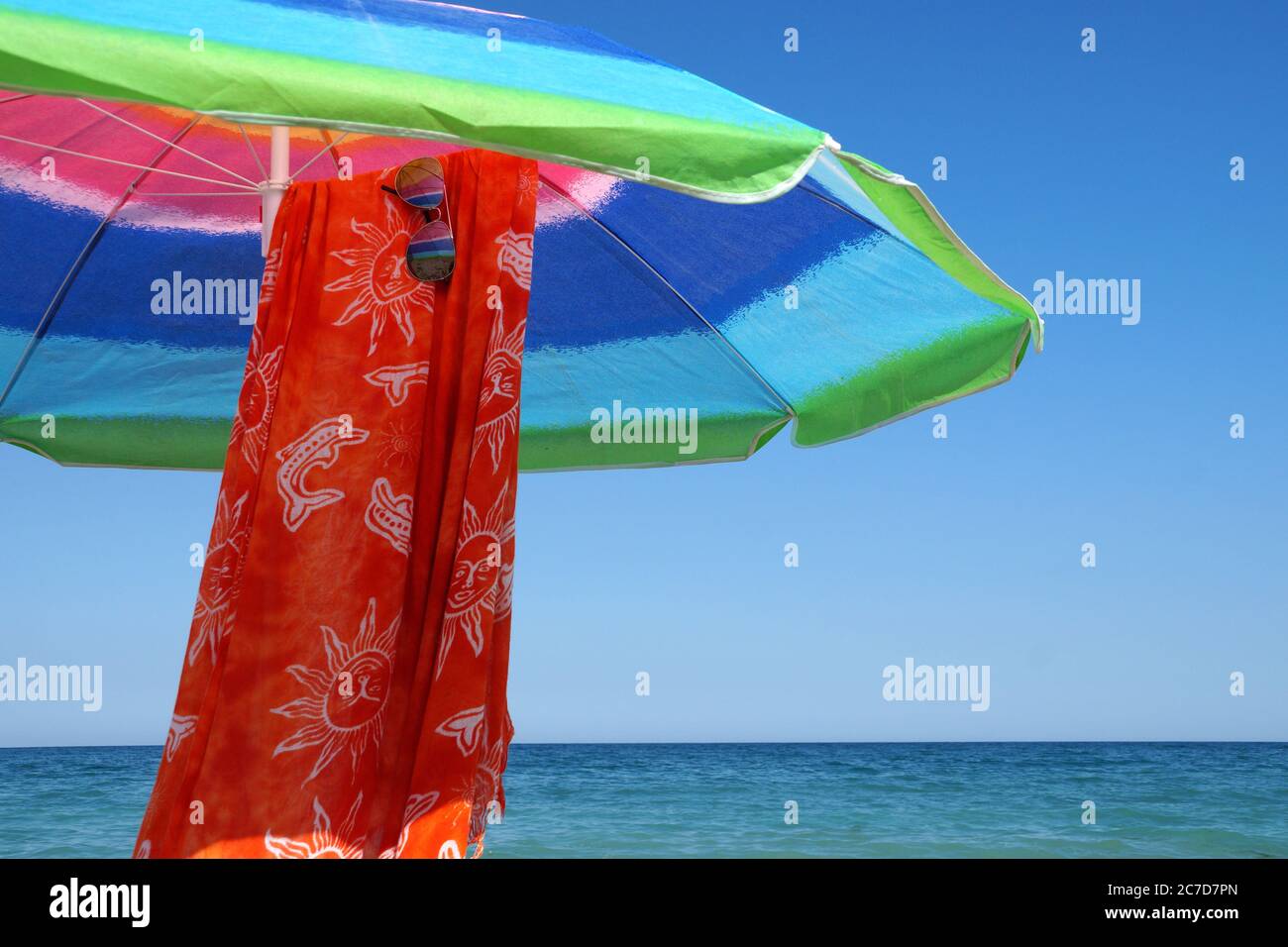 parasol, paréo et lunettes de soleil contre l'horizon marin et ciel clair, espace de copie. Banque D'Images