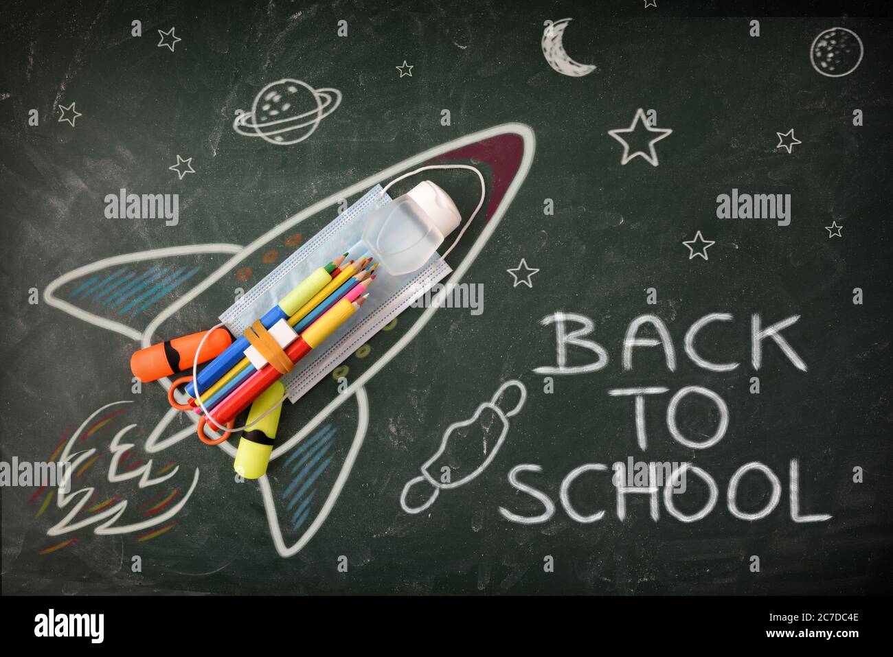 Créativité scolaire avec dessin sur tableau noir avec crayons de couleur et protections Covid-19 avec message de retour à l'école. Vue de dessus Banque D'Images