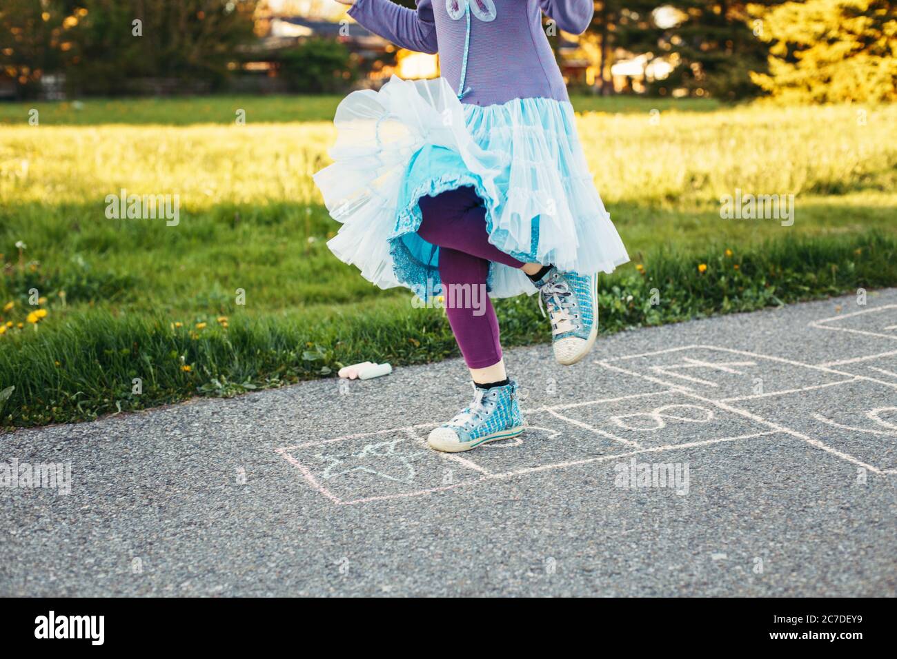 Gros plan de chld fille jouant saut de hopscotch en plein air. Jeu d'activités amusant pour les enfants sur l'aire de jeux à l'extérieur. Sports de rue de cour d'été pour les enfants. Banque D'Images