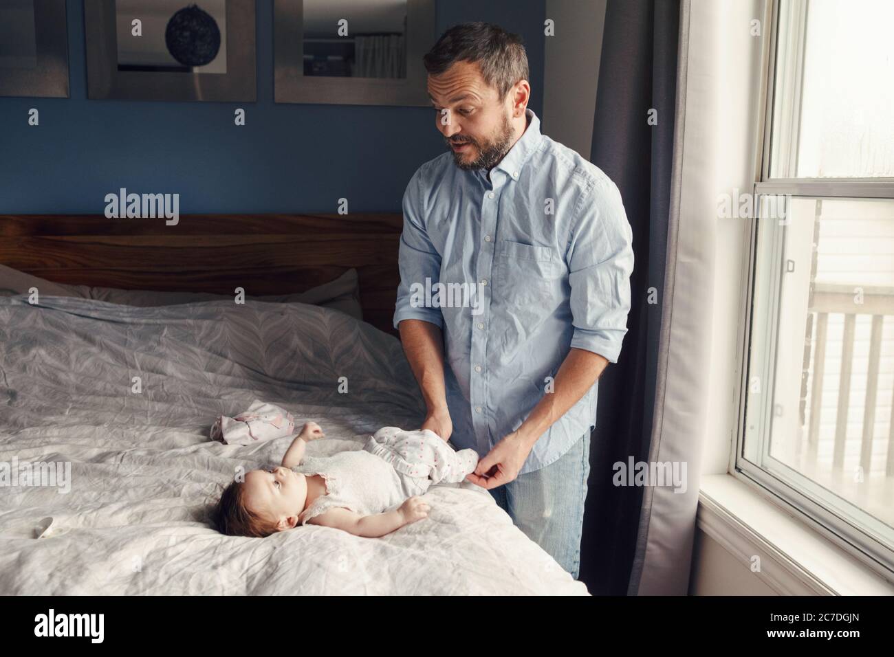 Le père caucasien d'âge moyen change les vêtements de couches pour le fils de fille de bébé nouveau-né. Homme parent prenant soin de l'enfant à la maison. Authentique style de vie candid Banque D'Images