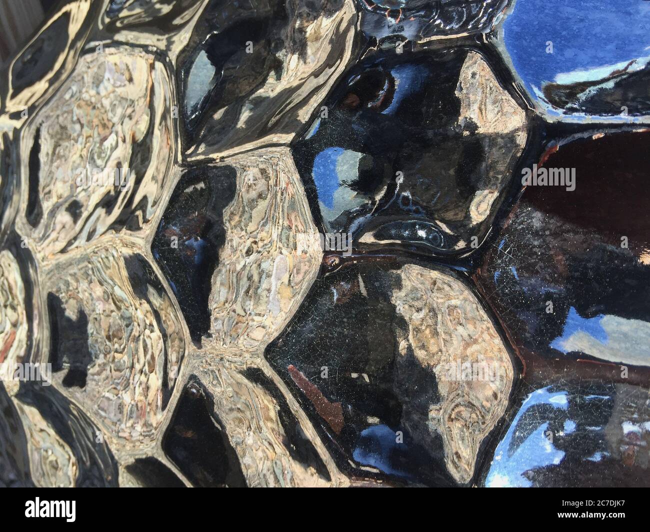 Photo macro de poterie noire brillante avec un nid d'abeille ou un motif hexagonal. Banque D'Images