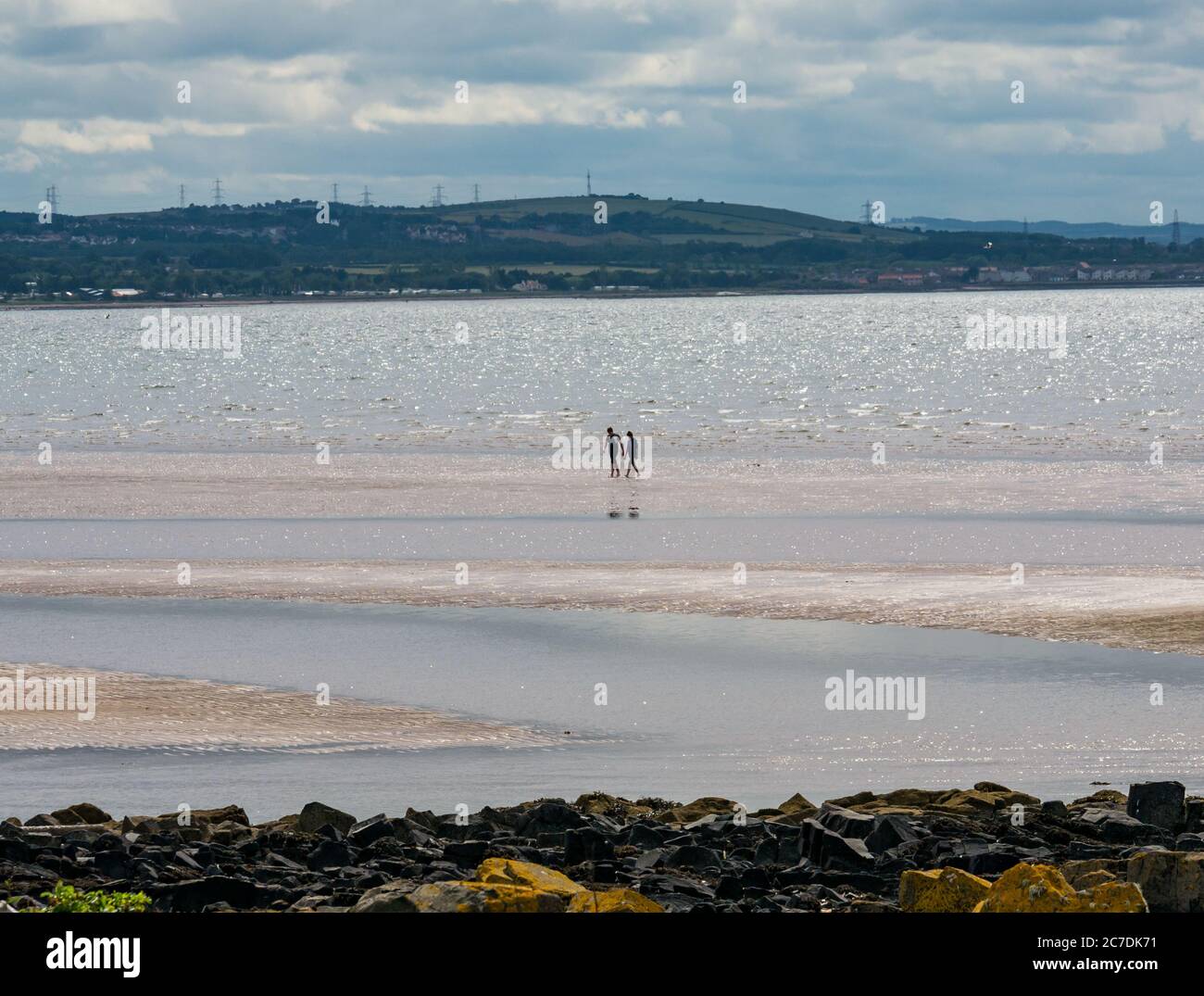 Firth of Forth, East Lothian, Écosse, Royaume-Uni, 16 juillet 2020. Météo britannique : soleil chaud le long de la côte du Forth. Deux personnes apprécient l'eau fraîche seule sur la plage sous le soleil brumeux tandis que la marée recule Banque D'Images