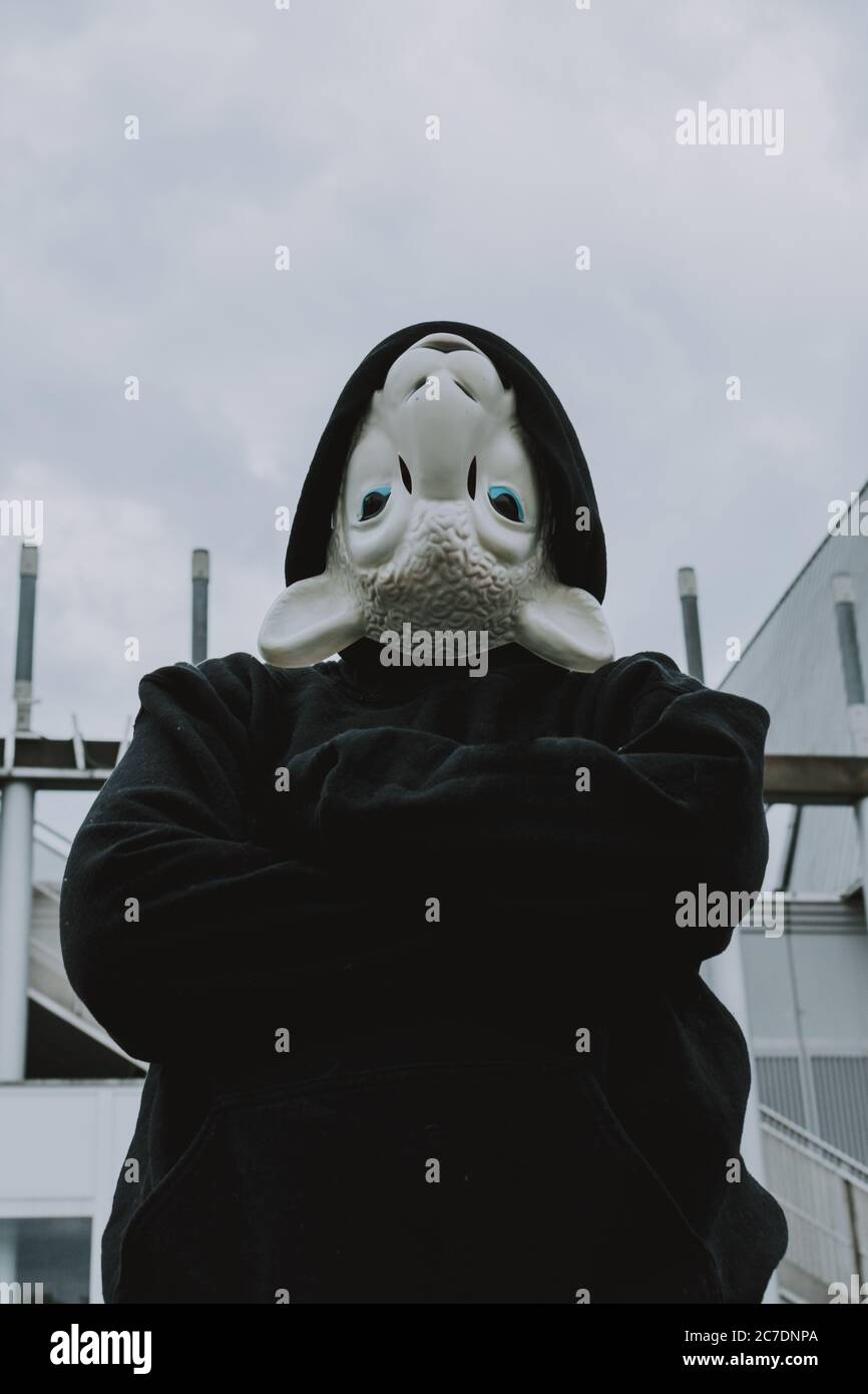 Plan vertical d'une personne à capuchon noir portant un mouton blanc masque à l'envers Banque D'Images